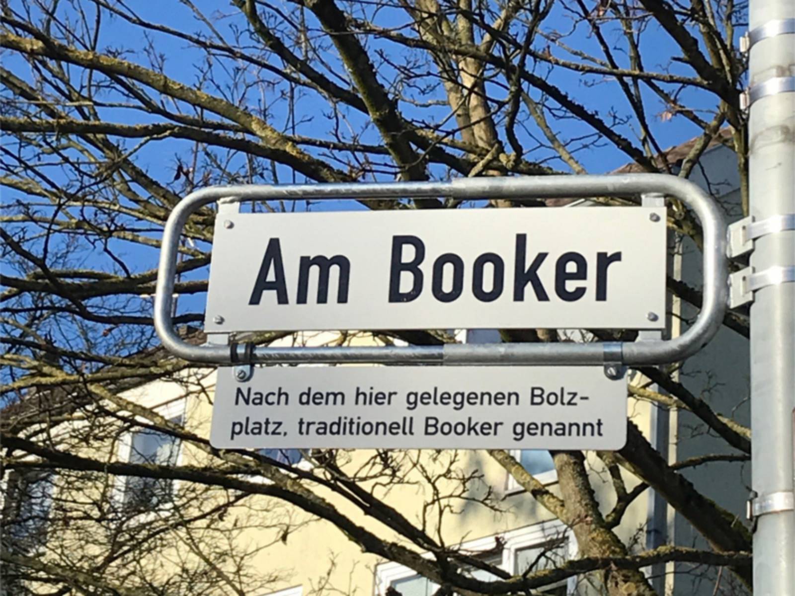 Straßenschild "Am Booker" mit Legendenschild dadrunter.